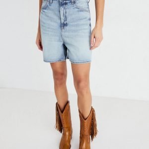Person wearing light-wash denim shorts and tan fringed cowboy boots against a plain white background.