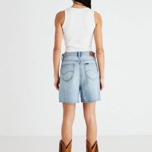 Woman seen from behind wearing a white tank top, light denim shorts, and brown fringe boots.