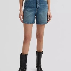 Person standing in mid-rise blue denim shorts and black knee-high boots against a light gray background.
