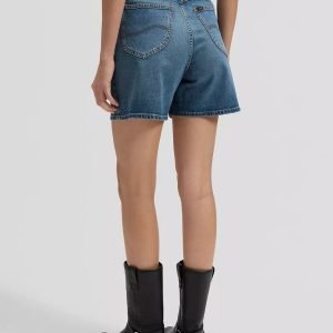 Back view of a person wearing blue denim shorts with back pockets and black knee-high boots.
