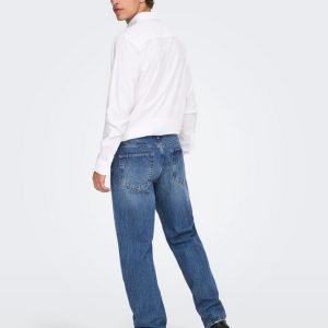 Man in a white shirt and blue jeans, seen from behind in a studio setting