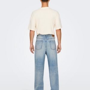 Man seen from behind wearing a cream short-sleeve T-shirt and light-wash, wide-leg jeans with beige sneakers.