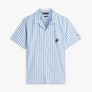 Light blue and white vertical striped short-sleeve button-down shirt with a small dark embroidered monogram on the left chest and a notched collar.