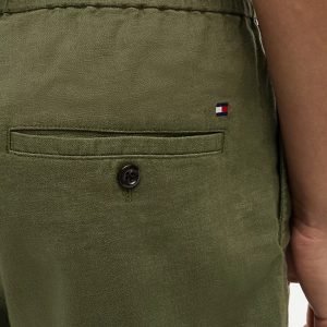 Close-up of olive-green pants with a back pocket and small Tommy Hilfiger flag logo on the right side.