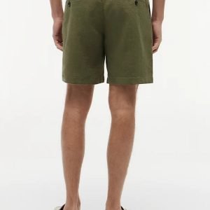 Back view of a person wearing olive-green shorts with two back pockets, a striped shirt, and cream espadrille-style shoes on a light background.