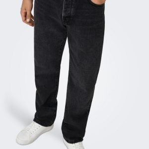 Full‑length view of a person wearing dark-wash jeans with white sneakers, standing against a light background.