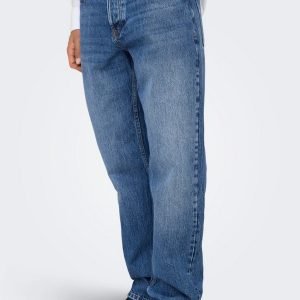 Full-length view of a person wearing faded blue jeans, a white shirt, and black shoes with one hand in a pocket.