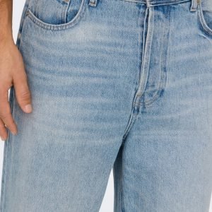 Close-up of light-wash blue jeans at the waist with a hand resting alongside the front pocket area.