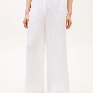Model wearing white wide-leg pants with a drawstring waist, paired with a beige top and brown sandals.