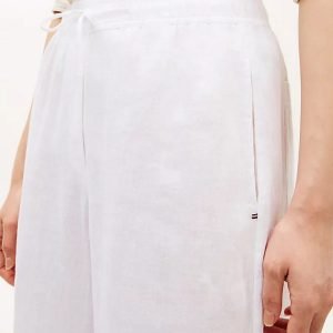 White wrap skirt tied at the waist with a side bow, straight silhouette, worn with a light top by a person.
