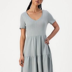 Woman modeling a light blue ribbed knit V-neck short-sleeve dress with a tiered skirt.