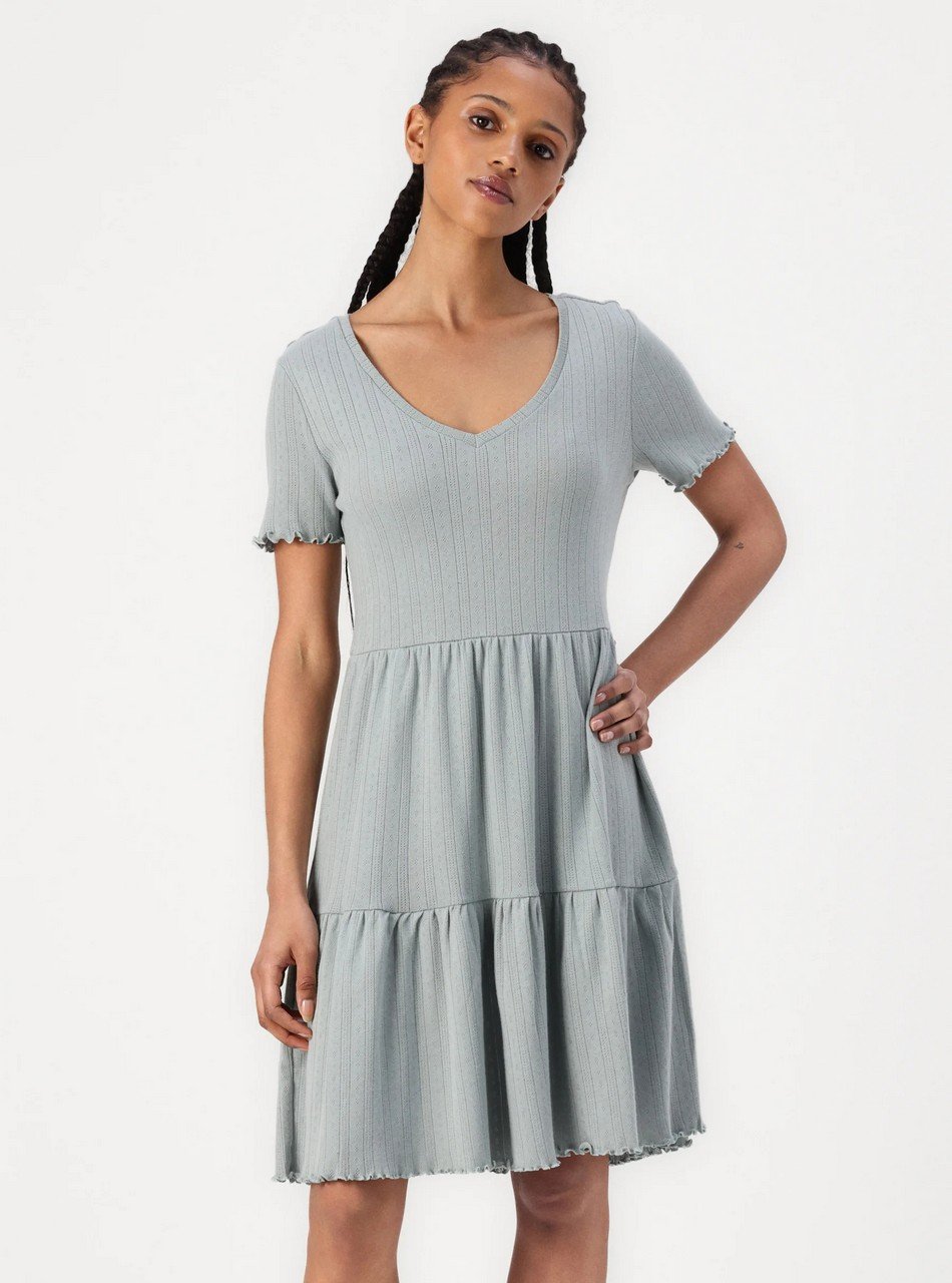 Woman modeling a light blue ribbed knit V-neck short-sleeve dress with a tiered skirt.