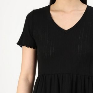Woman wearing a black short-sleeve V-neck dress with a gathered waist, shown from the chest down against a light background.