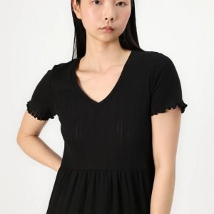 Asian woman wearing a black V-neck dress with short, ruffled sleeves, standing against a white background.