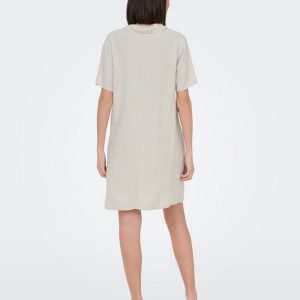 Back view of a woman in a light beige, knee-length short-sleeve dress with brown heels.