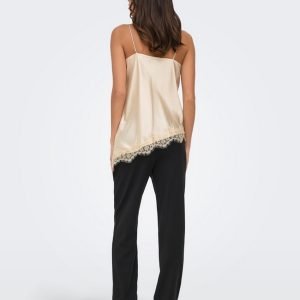 Back view of a woman wearing a beige satin camisole with lace hem and black pants, tan sandals.