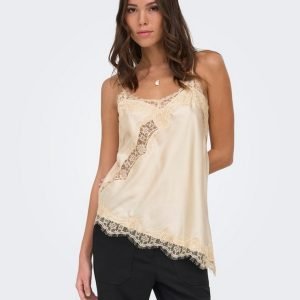 Beige satin camisole with lace trim worn by a woman standing in black pants; feminine, delicate top for a casual outfit.
