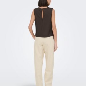 Woman seen from behind wearing a sleeveless dark brown top and light beige pants with subtle cutout/eyelet detailing at the back of the legs.