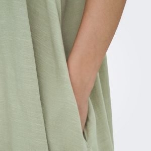 Close-up of a sage-green garment with a hand resting by a side pocket.
