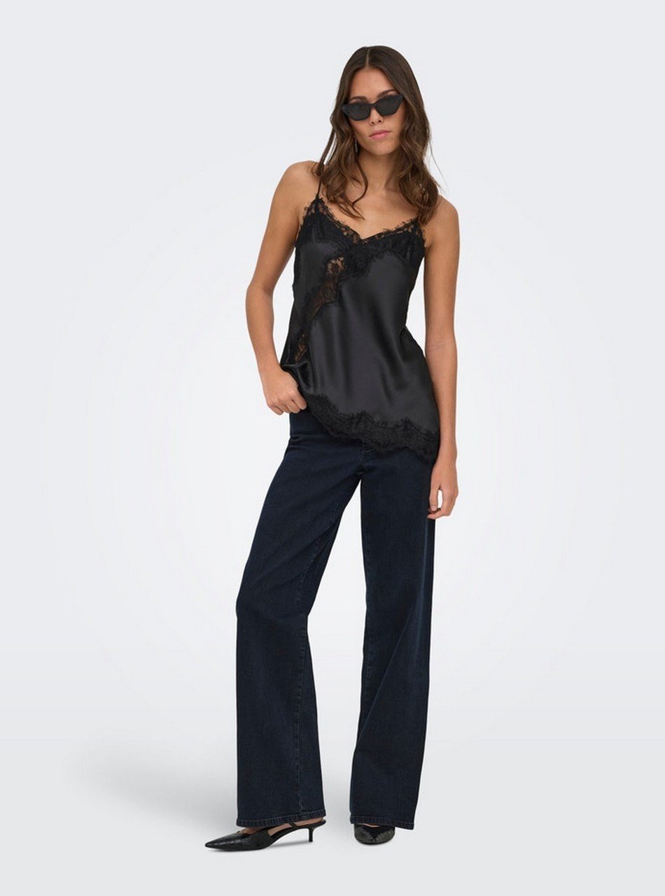 Model wearing a black satin camisole with lace trim, dark wide-leg jeans, and sunglasses.