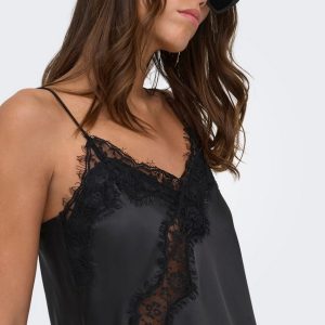 Woman wearing a black satin slip with lace trim and spaghetti straps, posed in profile with dark sunglasses.