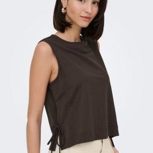 Woman modeling a dark brown sleeveless top with side ties, paired with beige pants, against a light background.