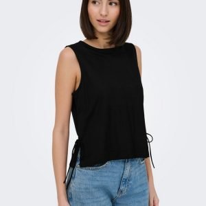 Woman wearing a sleeveless black top with side ties and light blue jeans, posing against a light background.